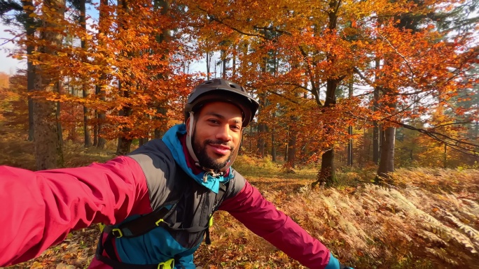 男性山地车骑手在阳光明媚的森林里自拍