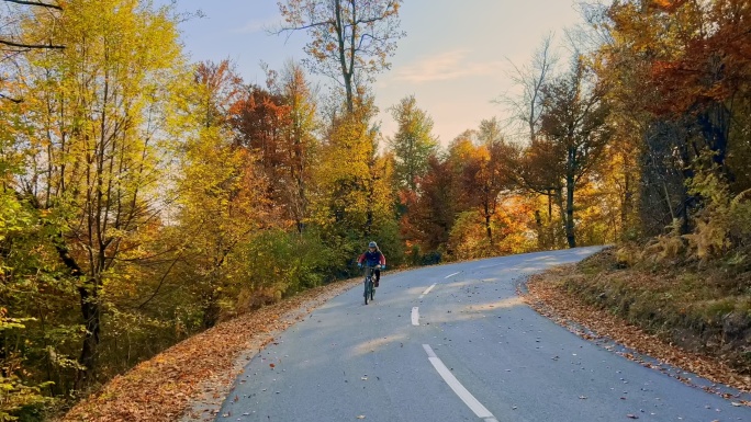 山地自行车手在阳光下沿着柏油山路骑行