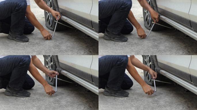 男子在乡村公路上更换汽车轮胎。