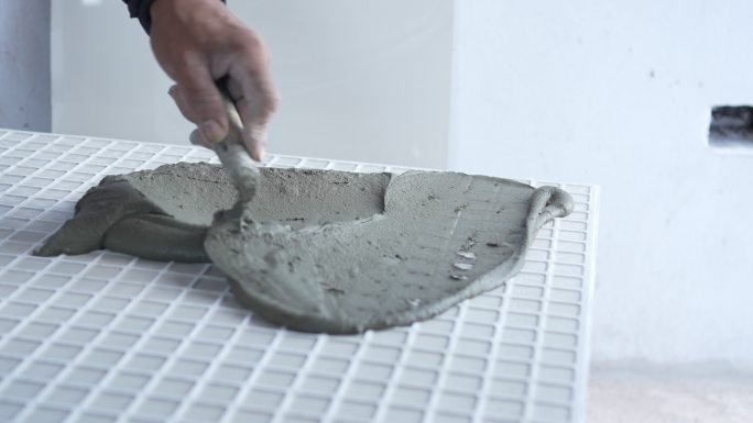 技工用抹子在瓷砖上涂抹水泥