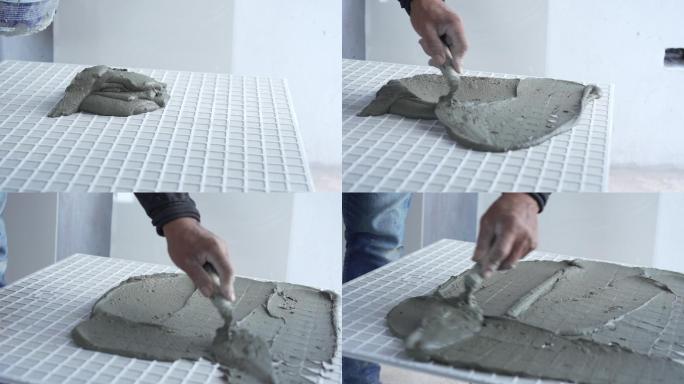 技工用抹子在瓷砖上涂抹水泥