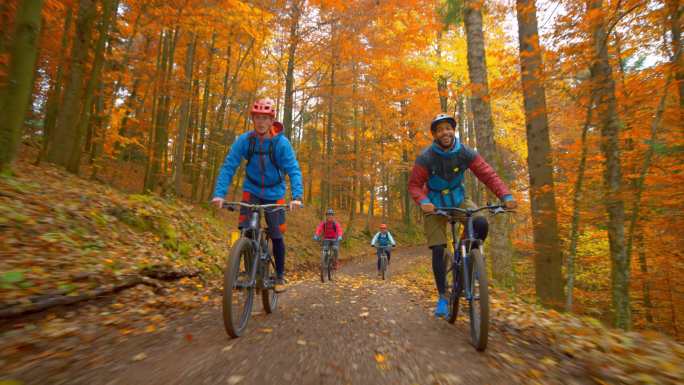 四个年轻人骑山地自行车穿过秋天的森林
