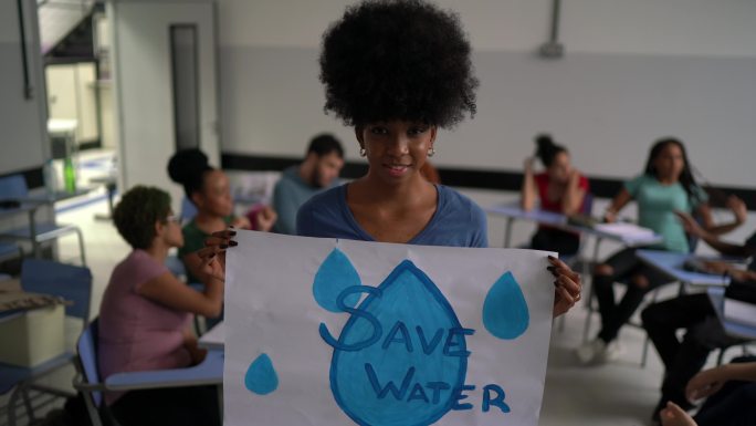 教室里拿着水资源保护海报的学生
