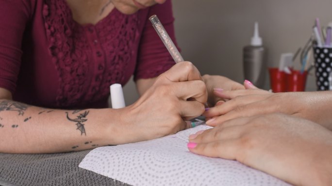 美容师在修指甲时给客户涂指甲油