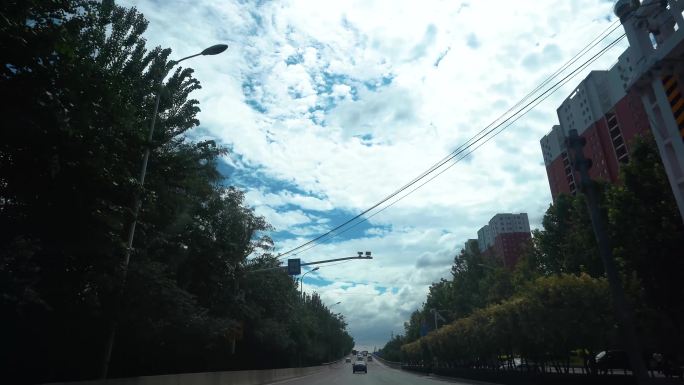 城市道路汽车行驶，车窗外风景蓝天白云