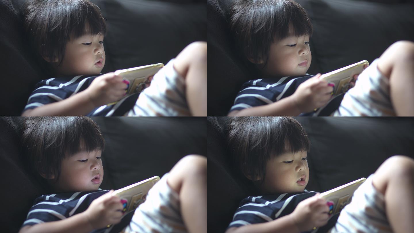 男婴在沙发上用智能手机看动画片