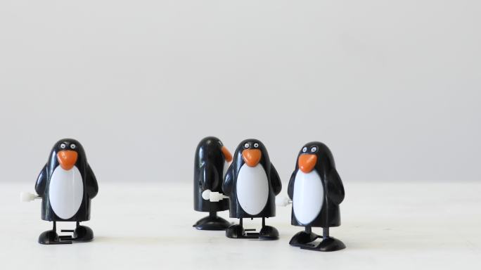 四只塑料企鹅在白色表面上随机移动