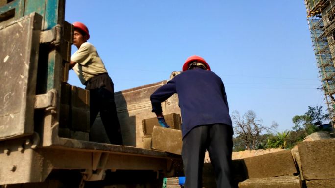 基建工地建筑装卸工卸水泥砖工地忙碌的工人