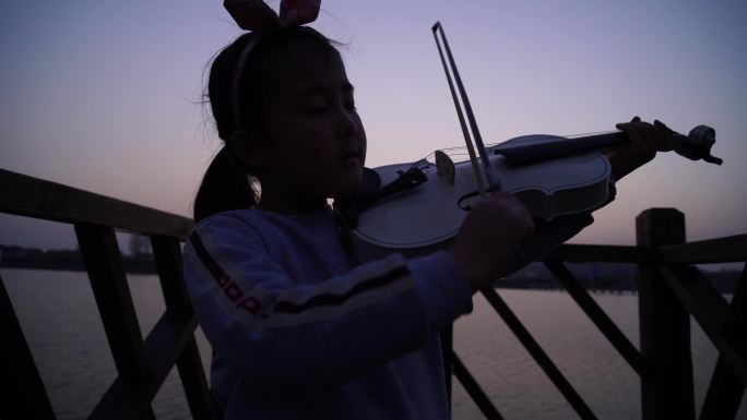 夕阳下小女孩河边拉小提琴一