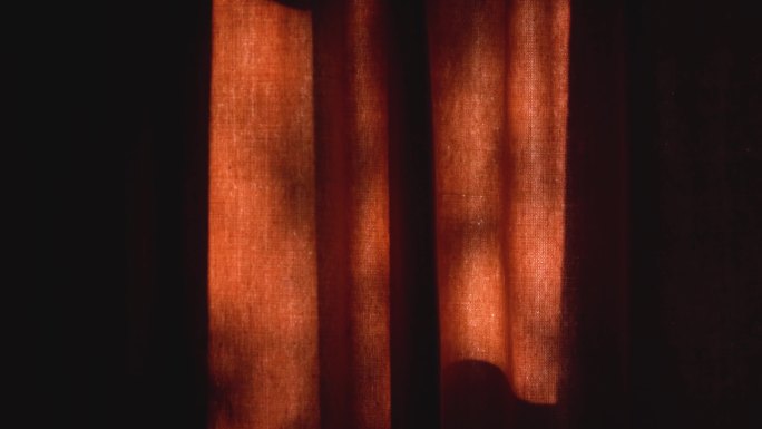 阳光透过一座乡村住宅的红色窗帘