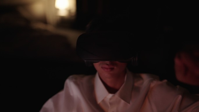 年轻人晚上使用虚拟现实眼镜玩游戏