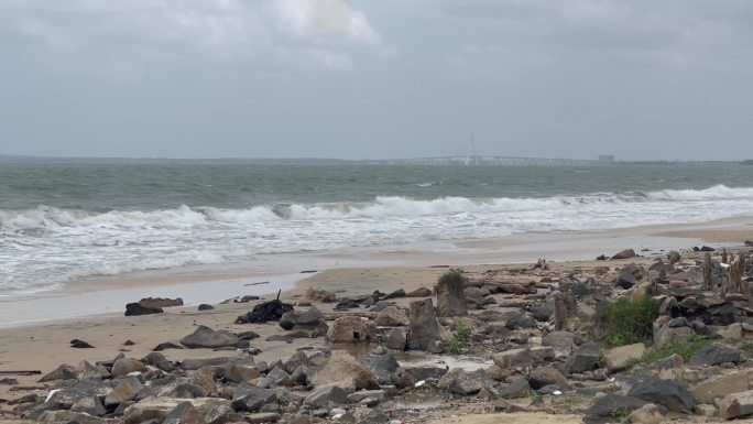 海边沙滩石头海浪远处大桥