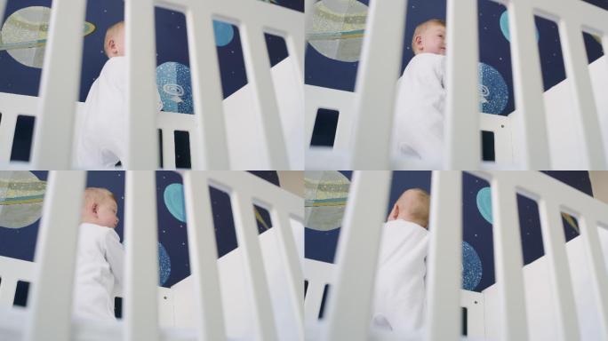 一个可爱的男婴站在家里的婴儿床上玩耍