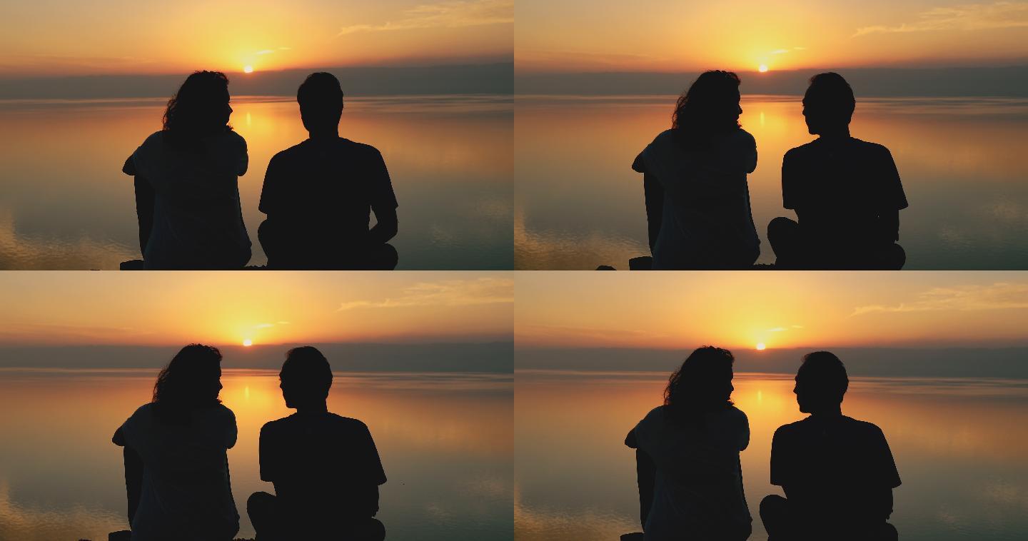 这对年轻夫妇凝视着约旦死海上方美丽的日落