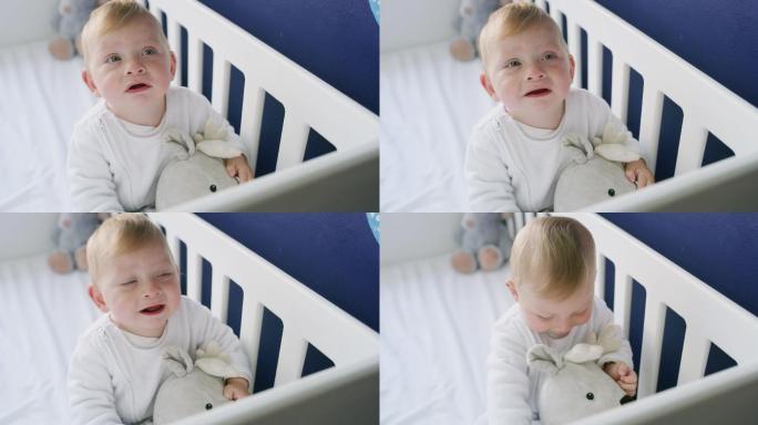 可爱的小男孩在婴儿床上玩泰迪熊