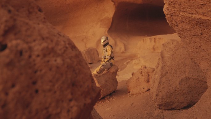 探索洞穴的女宇航员，坐在岩石上