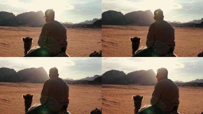 年轻男子在沙漠骑骆驼