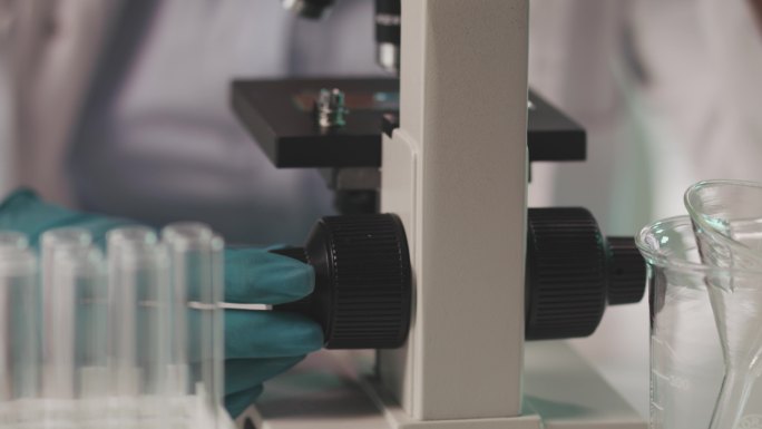 科学家在分析样品时在显微镜上调整焦距