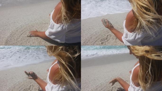 一个女人在海滩上玩沙子的慢镜头。