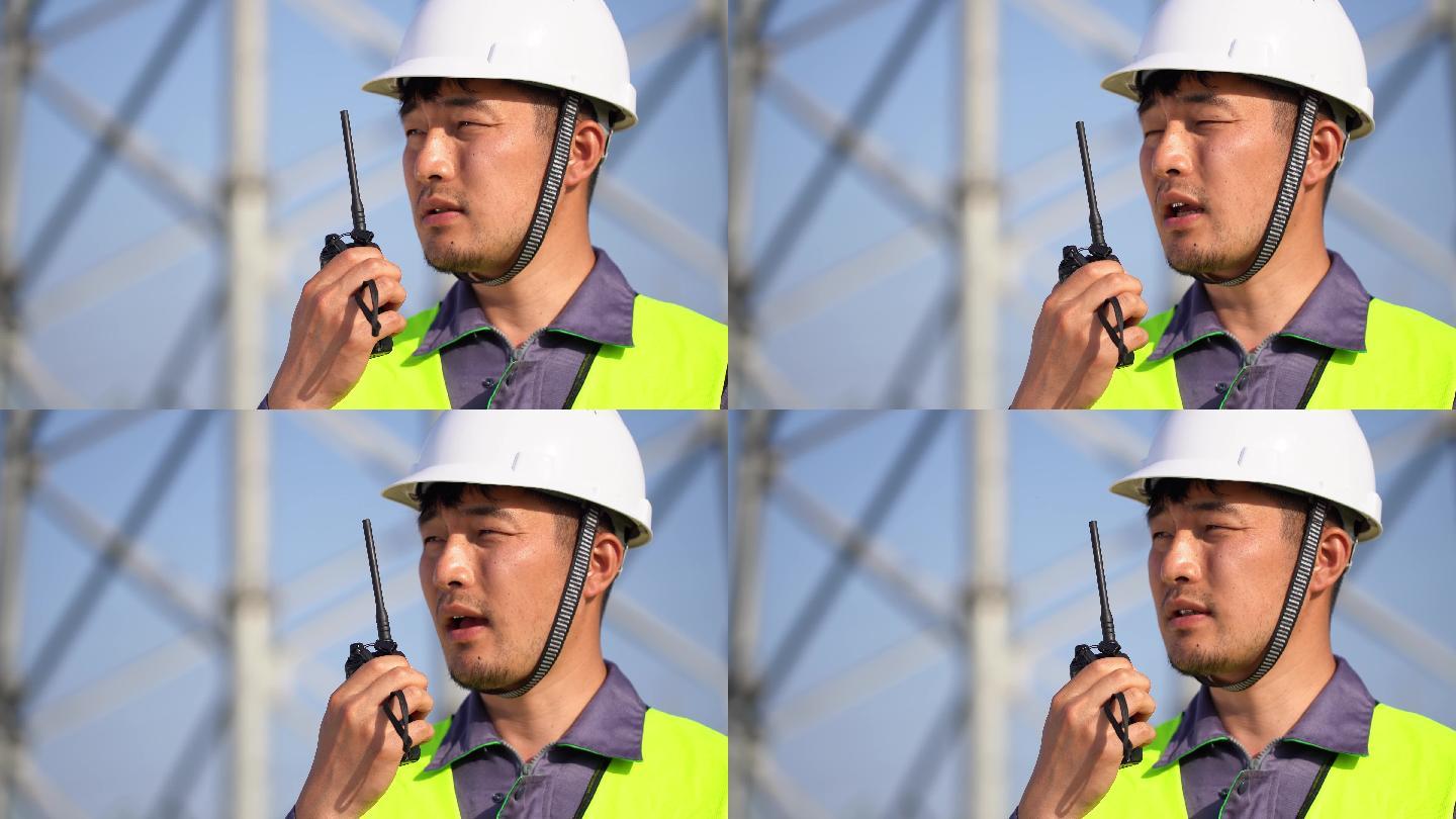 年轻工程技术人员在高压线塔使用对讲机通话