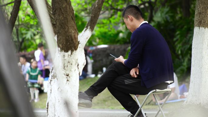 男子坐在公园里玩手机