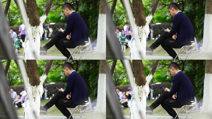 男子坐在公园里玩手机