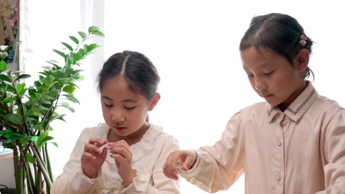 两名认真玩剪纸游戏的中国女孩