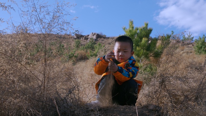 小男孩在山坡上独自玩泥巴
