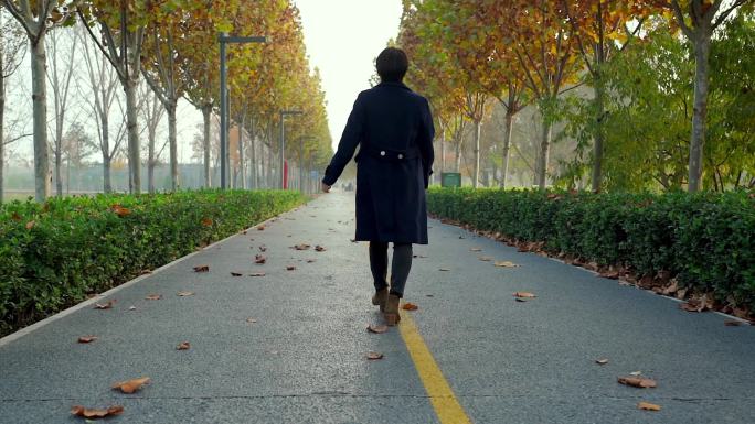 秋天独自走在公园小路上的中国女性