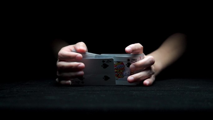 从黑暗中伸出一双玩纸牌的手