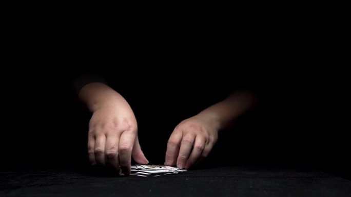 从黑暗中伸出一双玩纸牌的手