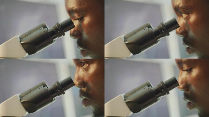 非洲裔科学家使用显微镜。脸部特写。电脑屏幕背景