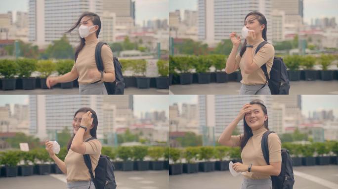 快乐的亚洲女人走在城市街道上，摘下防护口罩。2019冠状病毒疾病的终结已经结束。