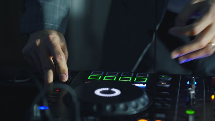 DJ的特写手在DJ混音台上调整各种音轨控制。