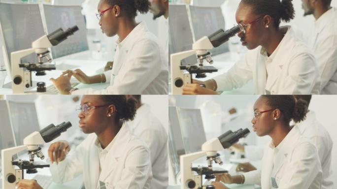 非洲，女科学家，拿着显微镜。她身后的实验室玻璃器皿。背景中的团队