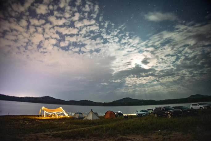 在月光星空下的湖泊边自驾游露营