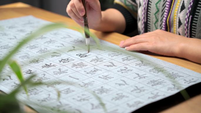 用字帖练习毛笔字的亚裔女性