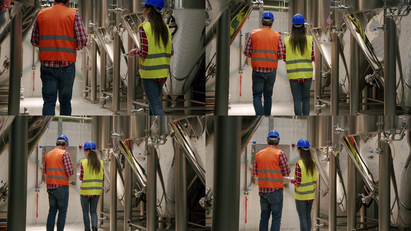 在现代啤酒厂的车间里，啤酒厂的工人们在一间设施室里行走，后视图