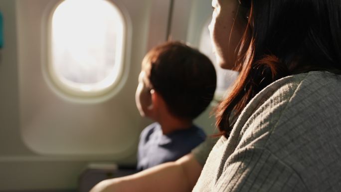 那男孩和他母亲坐在一起。商务飞机靠窗他看着窗户，兴奋地看着能坐飞机旅行。