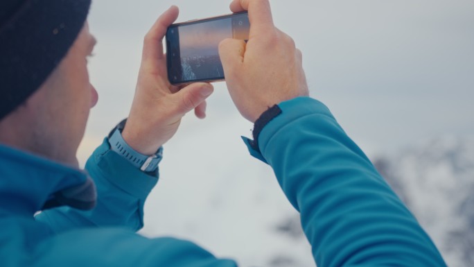 男子用手机拍摄雪山