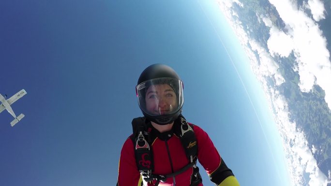 在云层和遥远的地平线上自由落体的女跳伞者