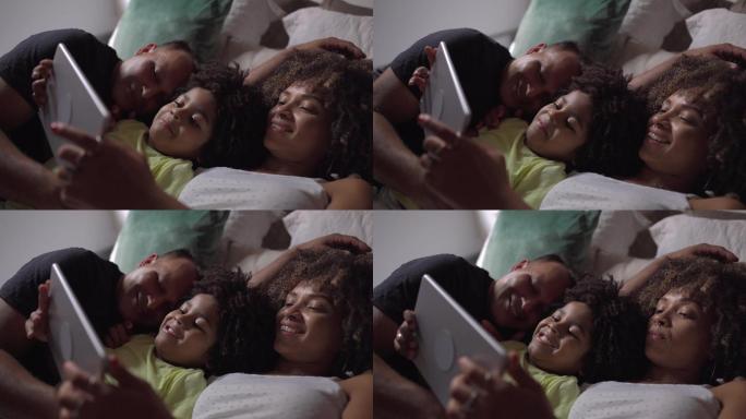 一家人躺在床上，在家里用数字平板电脑观看视频或电影