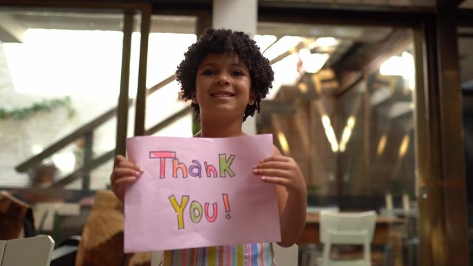 在家里拿着写着“谢谢”的纸的女孩——网络摄像头视角