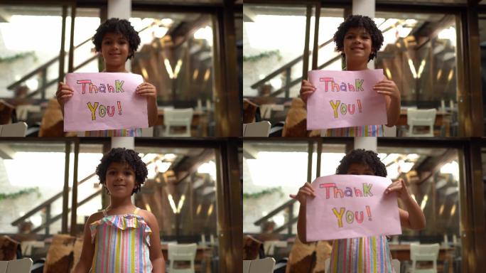 在家里拿着写着“谢谢”的纸的女孩——网络摄像头视角