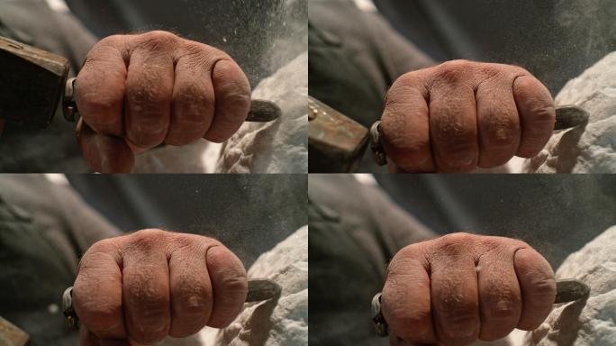 一位男性雕塑家在工作时拿着凿子的那只缓慢的手