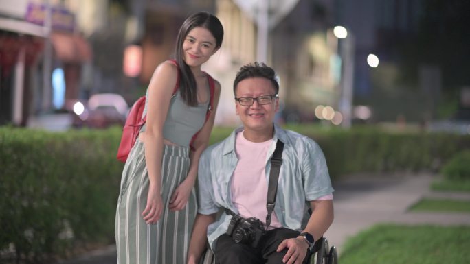 带着轮椅的亚裔中国游客和他的女朋友微笑着看着镜头