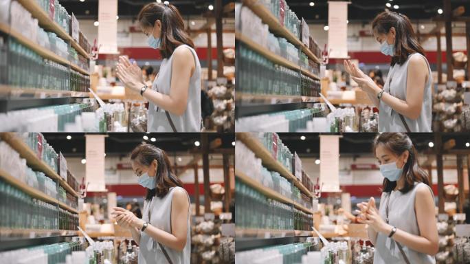 在商店零售店购物的年轻亚洲女性戴着口罩，选择化妆品，并在尝试之后和之前使用洗手液