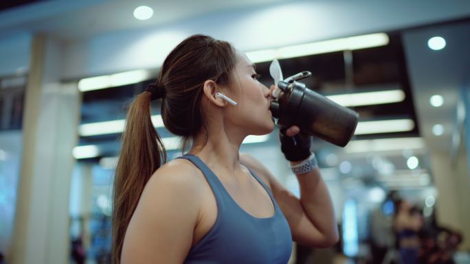 运动女性在健身房喝蛋白质奶昔