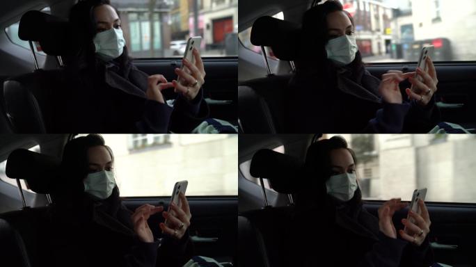 在旅途中，戴着口罩的女士正在汽车后座使用智能手机。