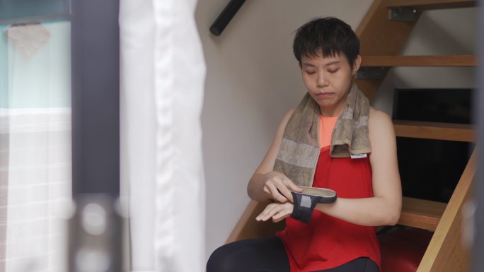 亚裔中国中年女子戴上智能手机，准备在straircase健身